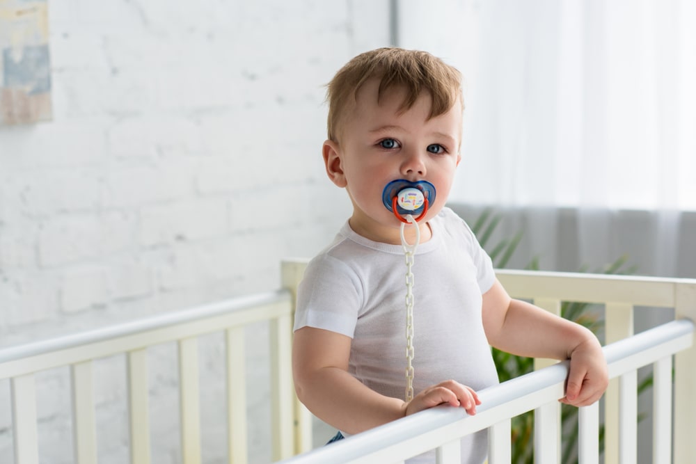 cute little baby boy with pacifier in baby crib